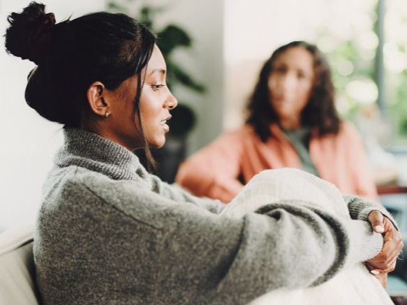 Woman sitting down and talking to someone.