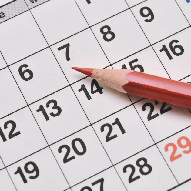 A calendar with a red pencil laying over it