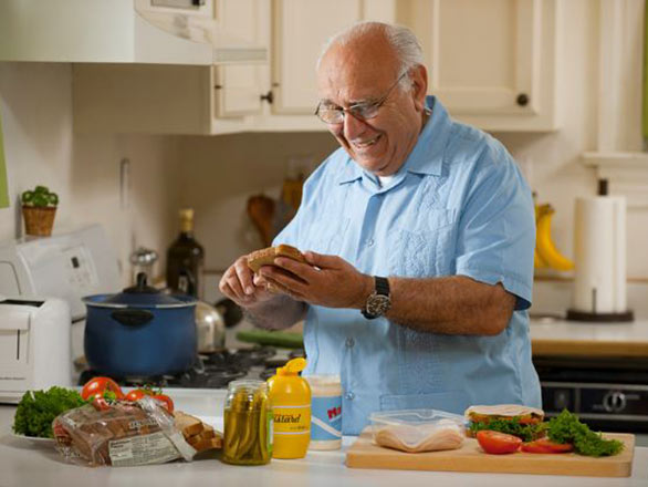 An older adult man prepares a sandwich