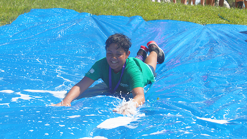Boy in 4-H water sliding at summer camp