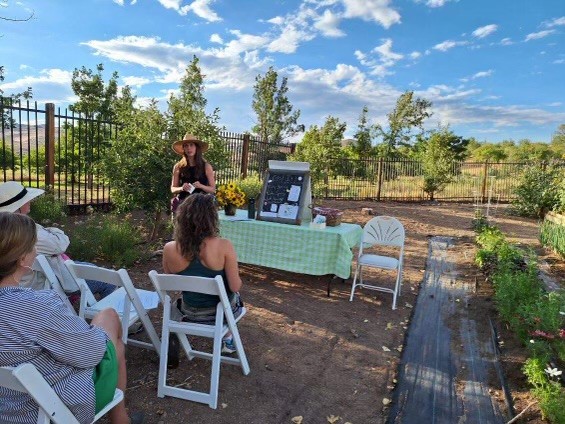 people standing in front of a table outside among trees.