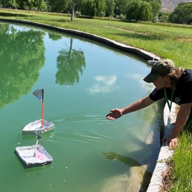 A teenage boy testing a craft boat in a pond