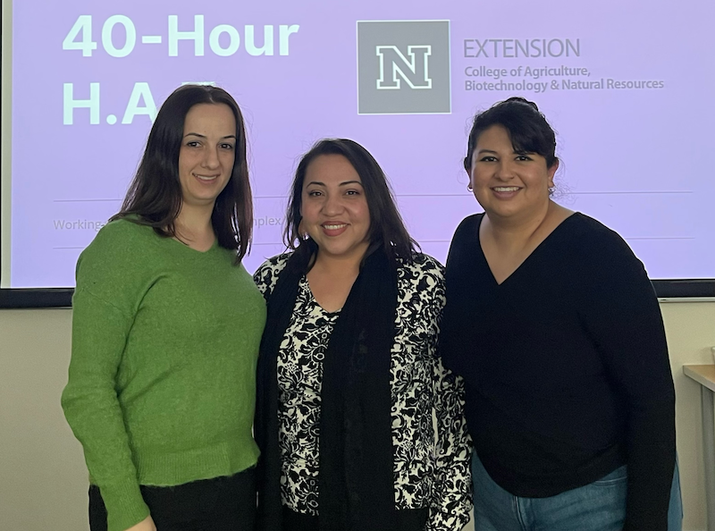 3 women standing in front of presentation slide