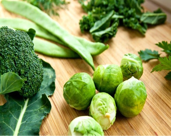 Broccoli, peas, brussel sprouts and kale on a wooden counter