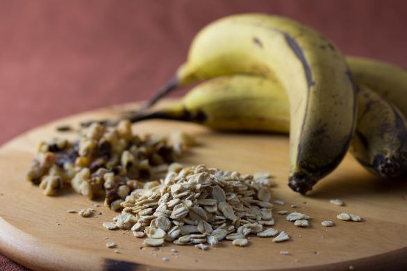 Two ripe bananas, walnut and oats on a wooden board