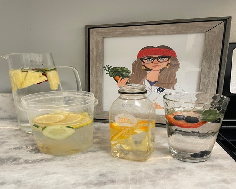 Chef Suzy and glasses of water with fruit and herbs.